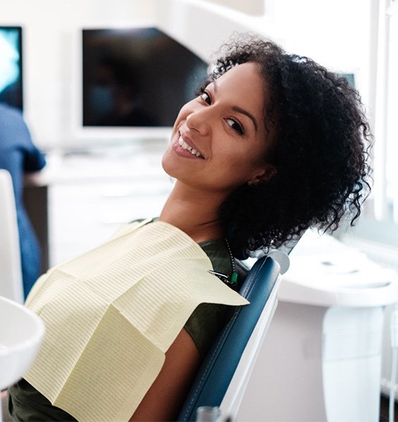 A young woman smiling while seated in the dentist’s chair