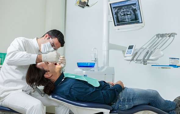 A dentist performing a checkup on a male patient