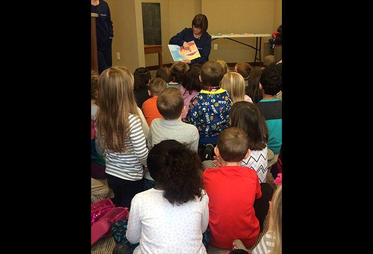 Team member reading to young kids