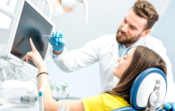 A female patient looking at a screen alongside her dentist