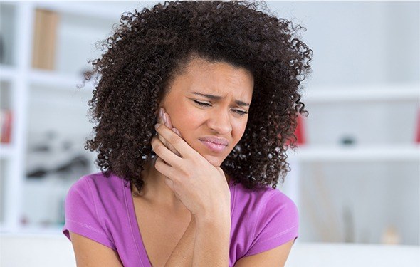 Woman holding cheek in pain