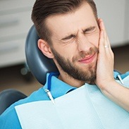 Man in dental chair holding cheek