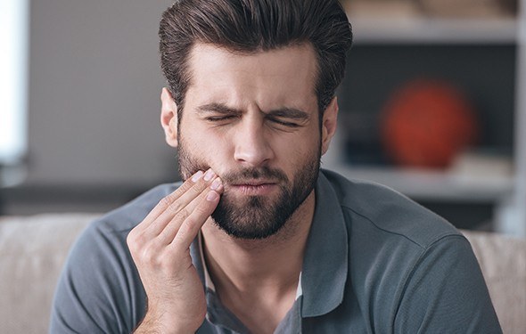 Man holding jaw in pain