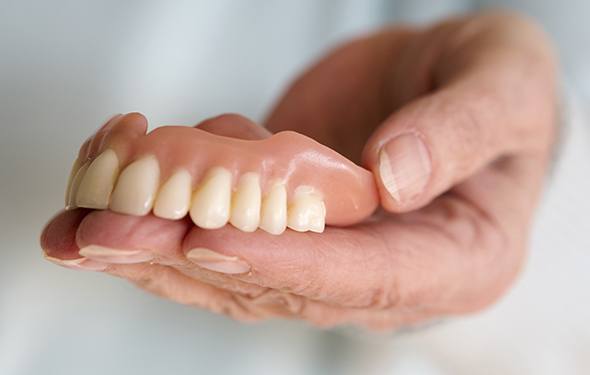 Hand holding full denture