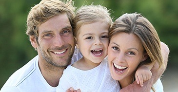 Mother father and child smiling outdoors