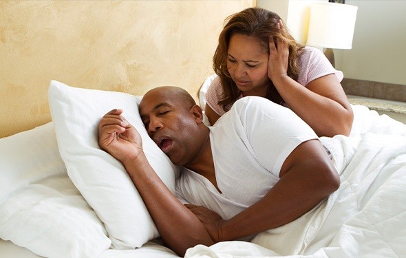 Frustrated woman in bed with snoring man